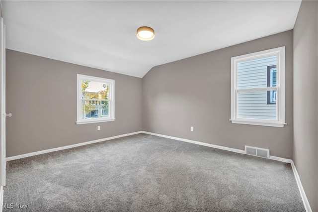 spare room with visible vents, carpet floors, baseboards, and vaulted ceiling