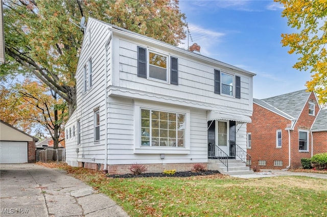 view of front of home with a front lawn, a chimney, and an outdoor structure