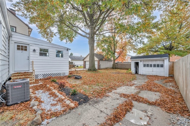 view of yard with cooling unit, driveway, a fenced backyard, entry steps, and an outdoor structure