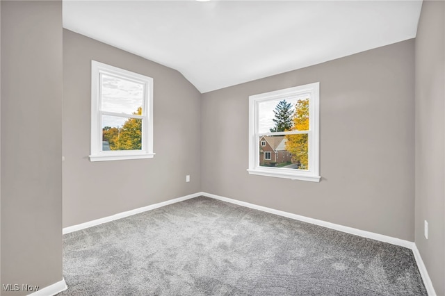 unfurnished room with a wealth of natural light, carpet, baseboards, and vaulted ceiling