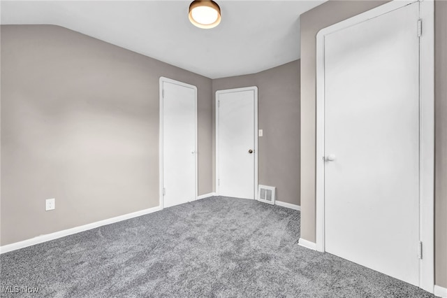 unfurnished bedroom with lofted ceiling, carpet, visible vents, and baseboards