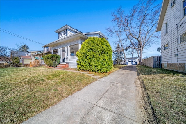 view of front of house featuring a detached garage, a porch, a front yard, and fence