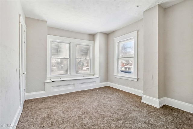 spare room with baseboards and carpet floors