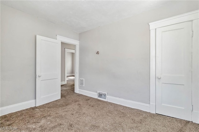 empty room with baseboards, visible vents, and carpet floors