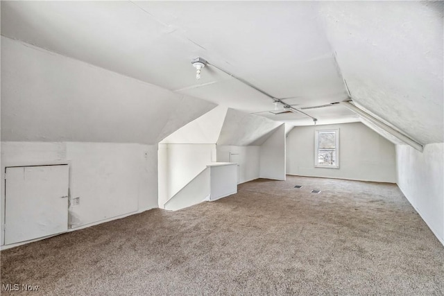 bonus room with carpet flooring and vaulted ceiling