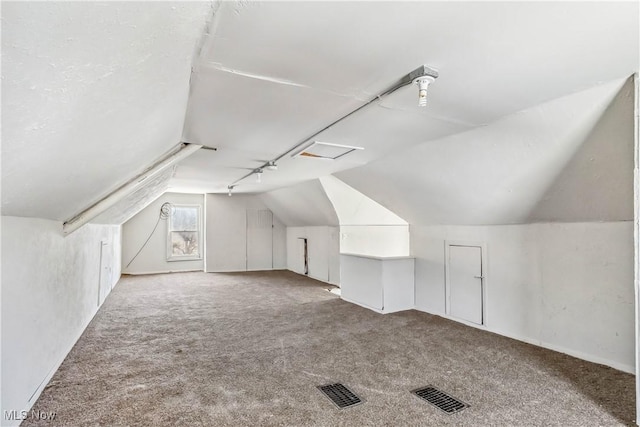 bonus room featuring lofted ceiling, carpet flooring, and visible vents