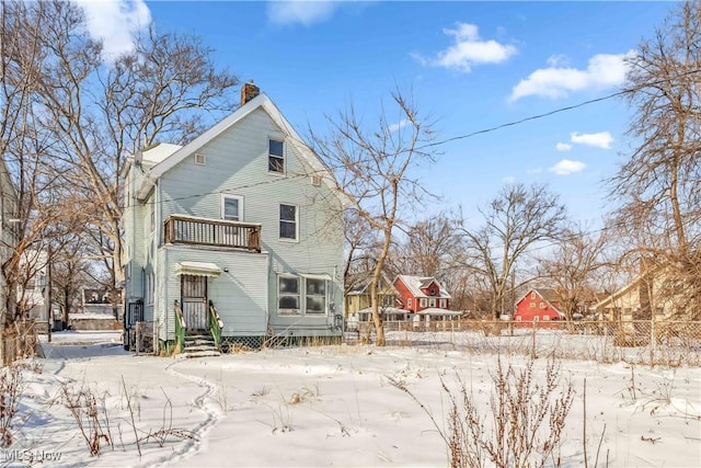 snow covered property with a chimney and fence