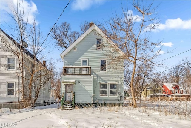 snow covered house with a chimney and fence