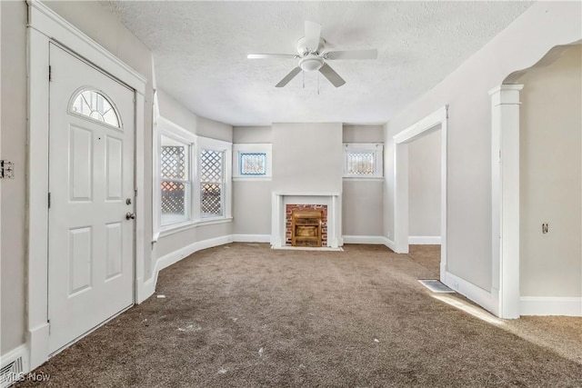 entrance foyer with a fireplace with flush hearth, carpet, and a textured ceiling