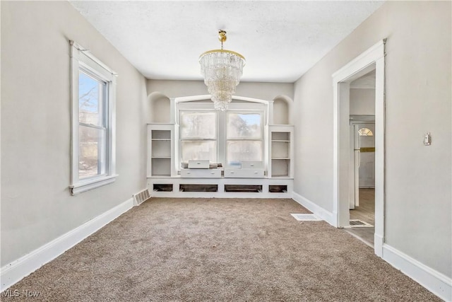 interior space featuring carpet flooring, visible vents, baseboards, and a chandelier