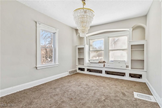 interior space featuring a chandelier, visible vents, baseboards, and carpet