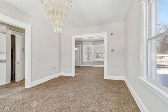 unfurnished dining area with baseboards, carpet floors, and a chandelier