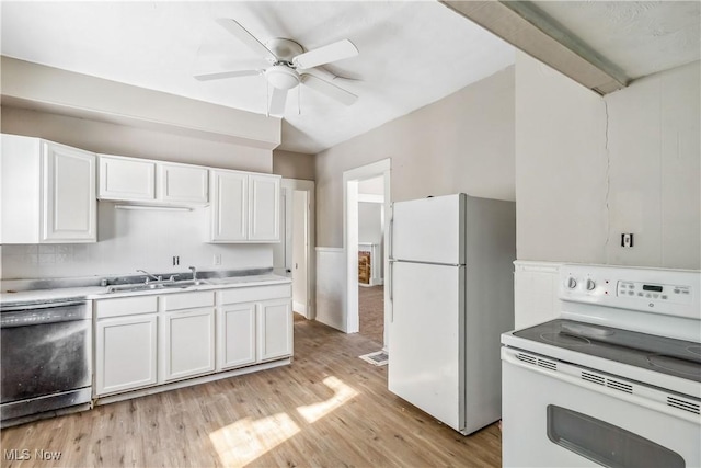 kitchen with white appliances, light wood finished floors, a sink, light countertops, and white cabinets