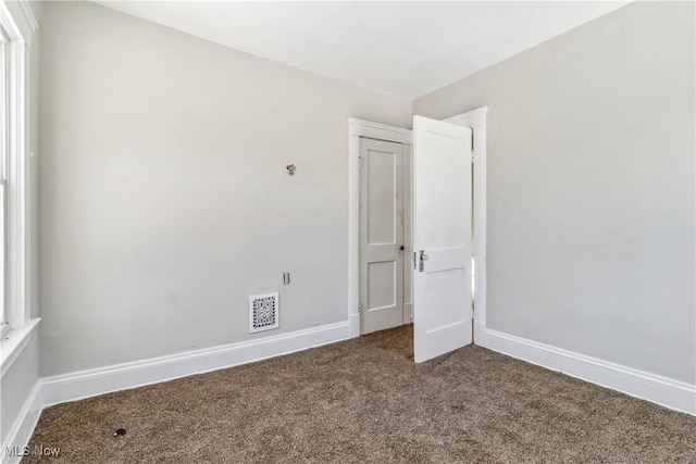 carpeted spare room with visible vents and baseboards