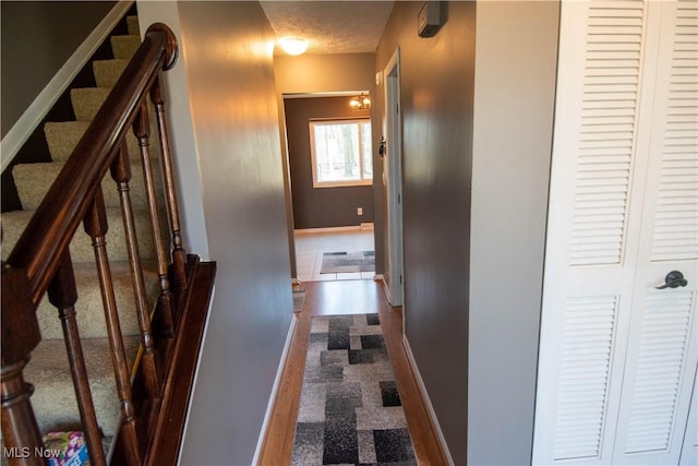 hallway with stairs, baseboards, and a textured ceiling