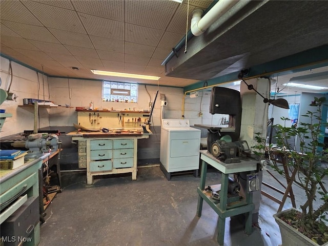 basement featuring concrete block wall, a workshop area, and washer / clothes dryer