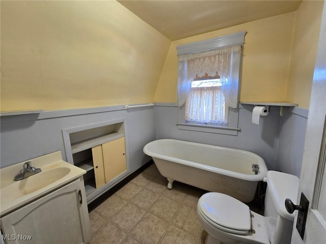 full bathroom with a soaking tub, wainscoting, toilet, and vanity