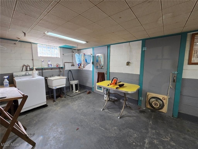 below grade area with concrete block wall, washer / clothes dryer, and a sink