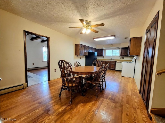 dining area featuring a baseboard heating unit, plenty of natural light, and light wood finished floors