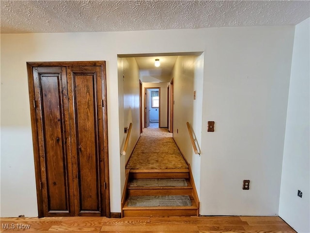 staircase featuring a textured ceiling and wood finished floors