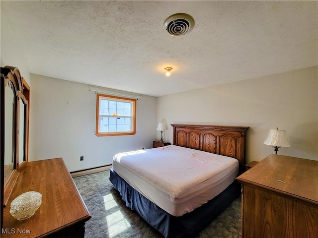 bedroom featuring visible vents, a textured ceiling, and a baseboard heating unit