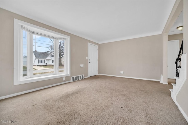 carpeted empty room with visible vents, stairs, and baseboards