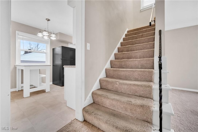 stairs with an inviting chandelier, baseboards, and carpet floors