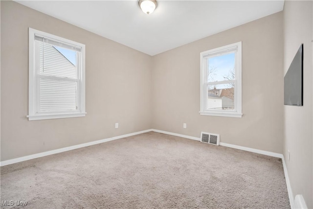 carpeted empty room featuring baseboards and visible vents