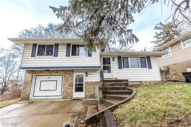 tri-level home featuring driveway, brick siding, a front lawn, and entry steps