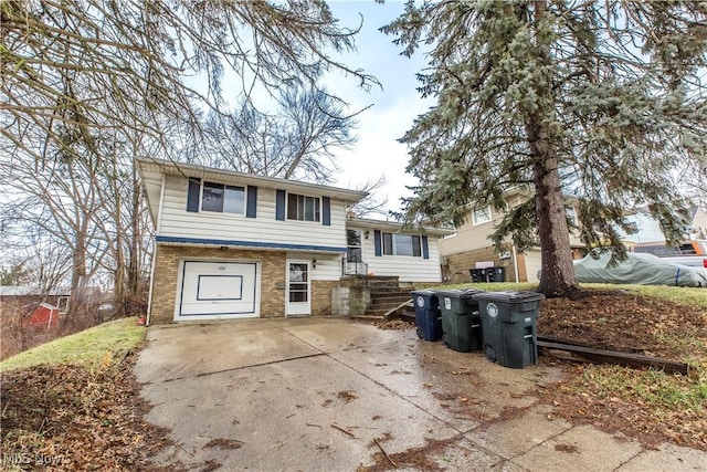 tri-level home featuring a garage, brick siding, and driveway