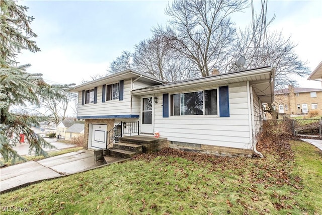 tri-level home with a front yard and fence