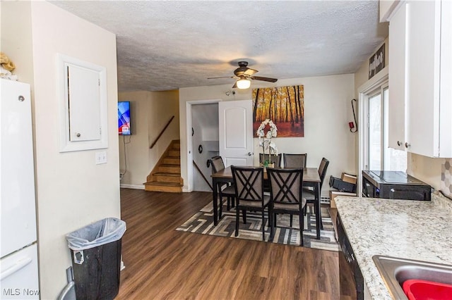 dining room featuring dark wood finished floors, stairway, a ceiling fan, and a textured ceiling