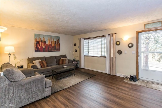 living room featuring visible vents, a textured ceiling, baseboards, and wood finished floors