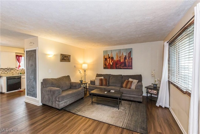 living area featuring a textured ceiling, baseboards, and wood finished floors