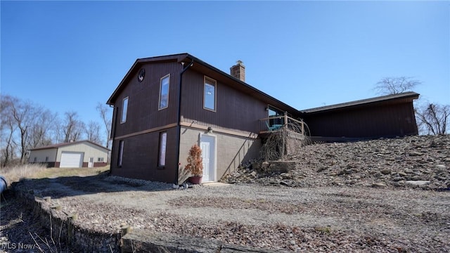 view of side of home with a garage, an outbuilding, and a chimney