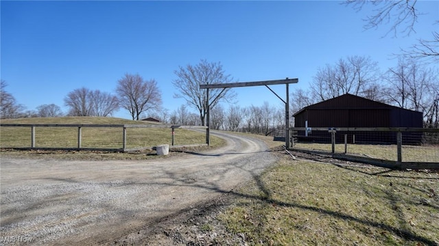 view of street with an outbuilding, driveway, and a rural view