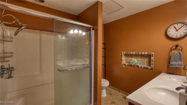 bathroom featuring a sink, toilet, a stall shower, and tile patterned floors