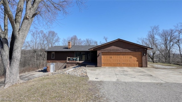 view of front of home with a shingled roof, an attached garage, driveway, and a chimney