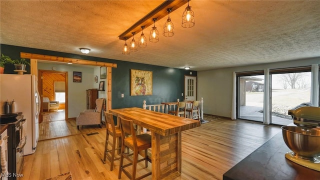 dining area with light wood-style flooring and a textured ceiling