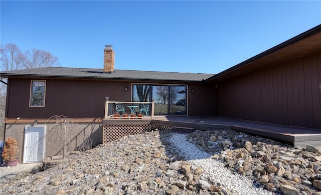 back of house with a wooden deck and a chimney