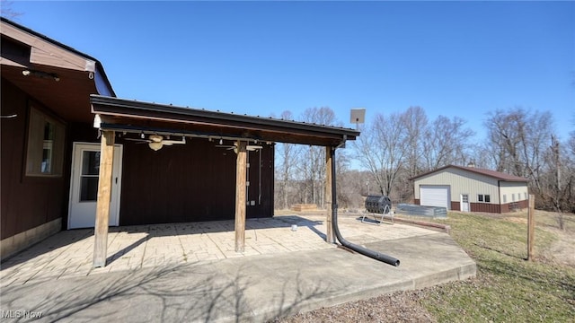 view of patio with an outdoor structure, a detached garage, and ceiling fan