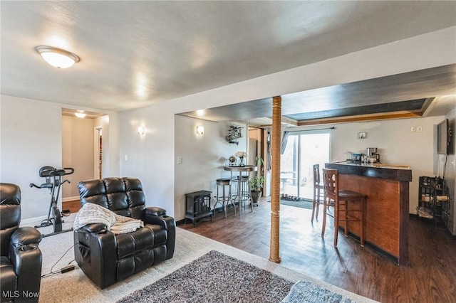 living room featuring a bar, baseboards, and dark wood-style flooring