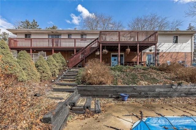 back of house featuring brick siding, stairs, and a deck