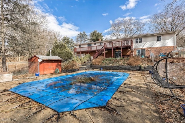 view of swimming pool with fence, stairs, an outdoor structure, a deck, and a storage unit