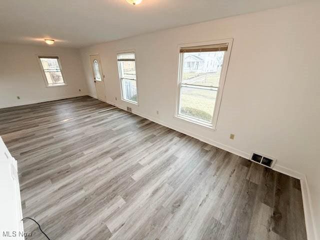 unfurnished living room with visible vents, baseboards, and wood finished floors