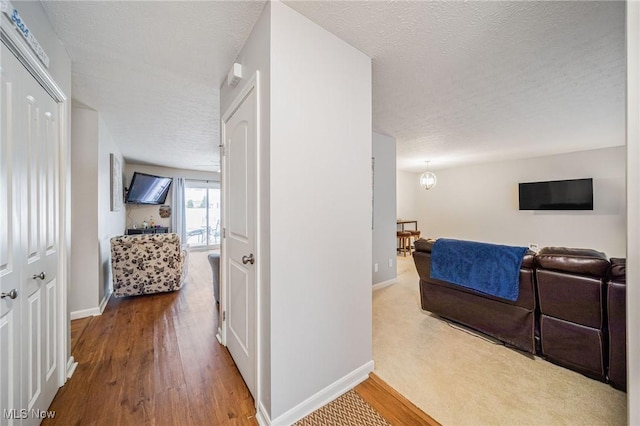 corridor featuring a textured ceiling, baseboards, and wood finished floors