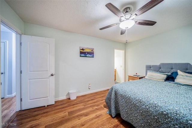 bedroom featuring ceiling fan, baseboards, a textured ceiling, and light wood-style flooring