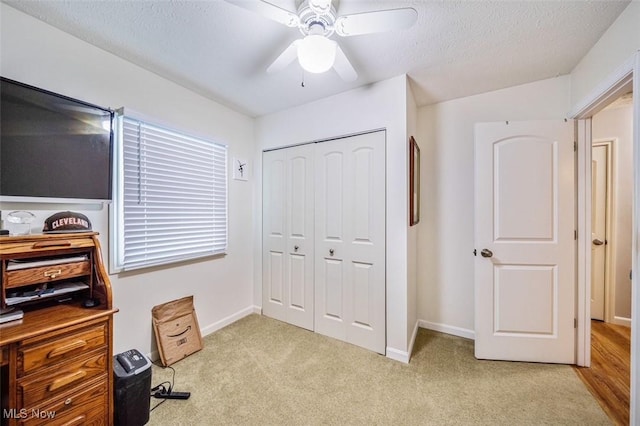 office area with baseboards, light colored carpet, a textured ceiling, and a ceiling fan