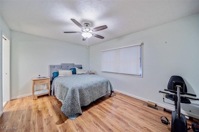 bedroom featuring a ceiling fan, wood finished floors, baseboards, and a textured ceiling