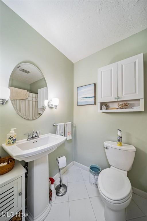 full bath with tile patterned flooring, a textured ceiling, toilet, and baseboards